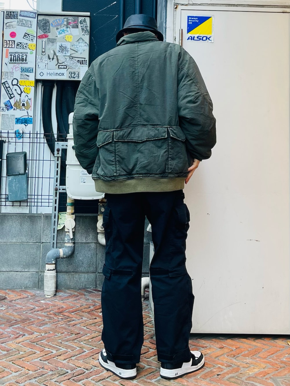 グリーン系のミリタリージャケット、グレー系のTシャツ/カットソー、ブラック系のカーゴパンツを着用したメンズの冬コーディネートの2枚目の写真