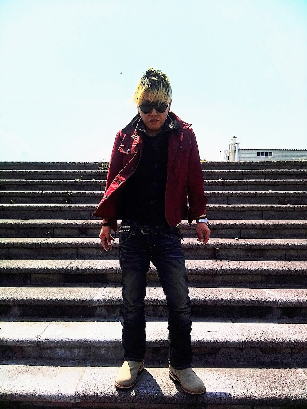 レッド系のデニムジャケット、ブラック系のベスト、ブラック系のTシャツ/カットソーを着用したメンズの春コーディネートの2枚目の写真