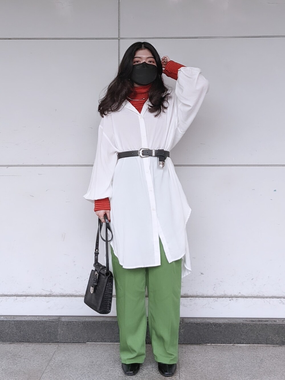 グリーン系のスラックス、ホワイト系のシャツ/ブラウス、オレンジ系のニット/セーターを着用したレディースの冬コーディネートの2枚目の写真