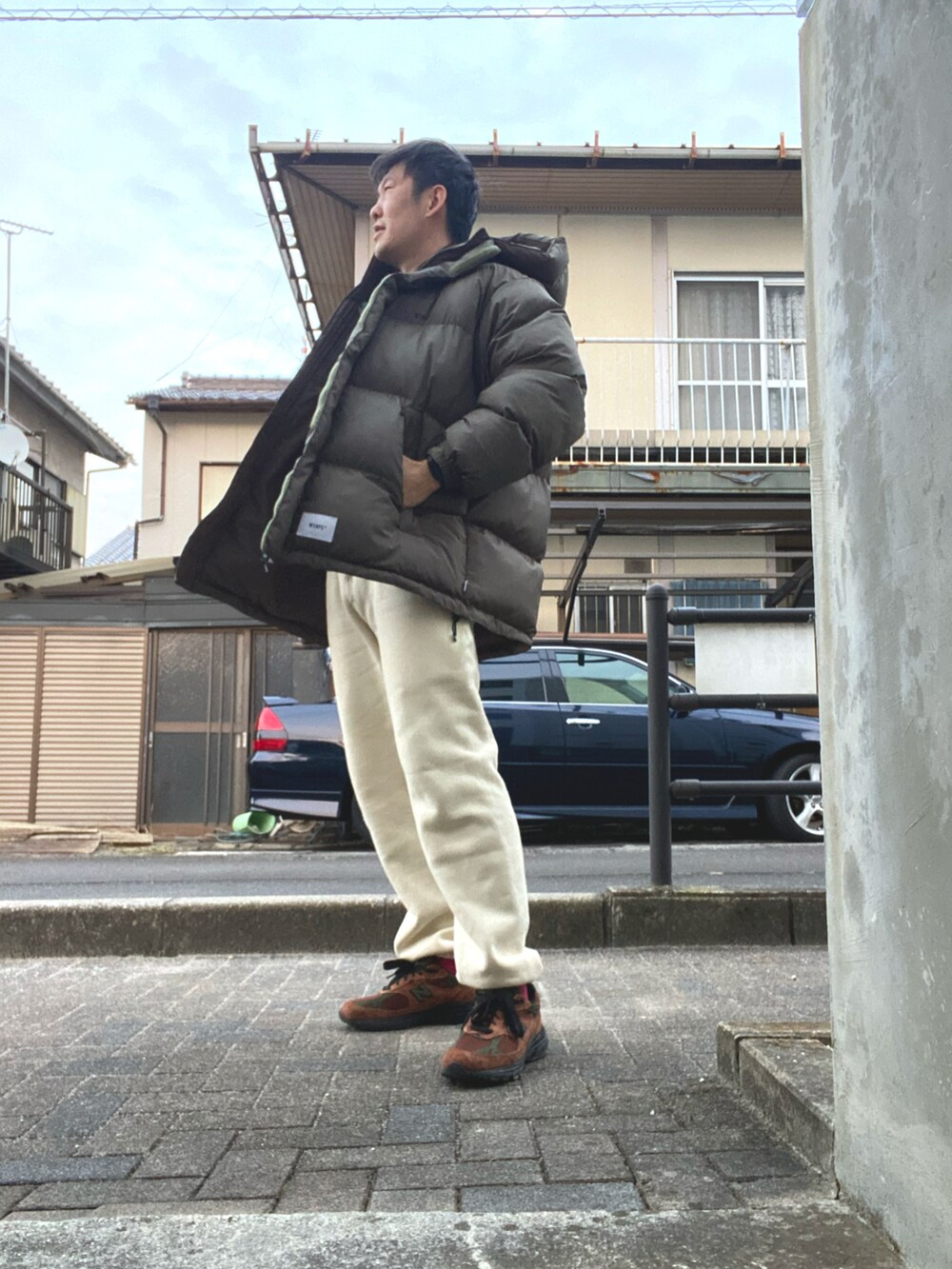 グリーン系のダウンジャケット/コート、ゴールド系のTシャツ/カットソー、ホワイト系のスウェットパンツを着用したメンズの冬コーディネートの2枚目の写真