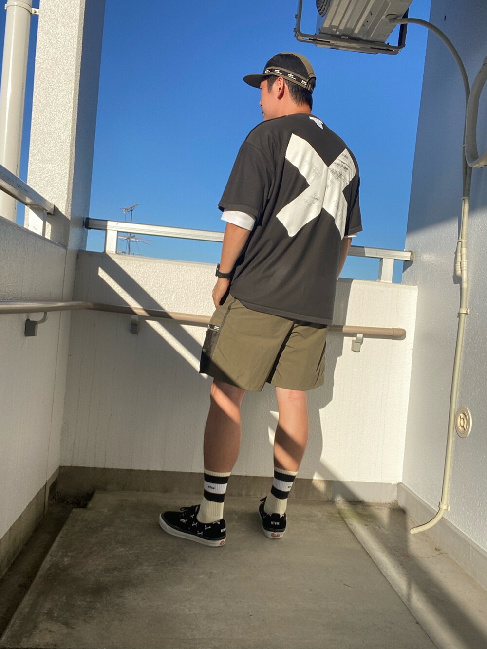 ブラック系のTシャツ/カットソー、グリーン系のパンツ、ブラック系のスニーカーを着用したメンズの夏コーディネートの2枚目の写真