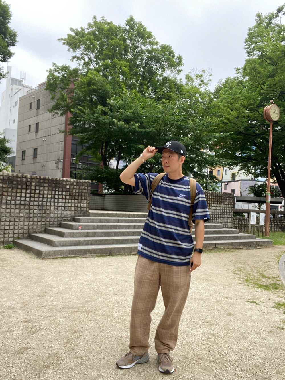 ブルー系のTシャツ/カットソー、ベージュ系のパンツ、ブラック系のキャップを着用したメンズの夏コーディネートの2枚目の写真