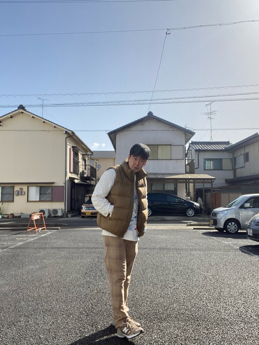 ベージュ系のダウンジャケット/コート、ベージュ系のパンツ、ベージュ系のスニーカーを着用したメンズの春コーディネートの2枚目の写真