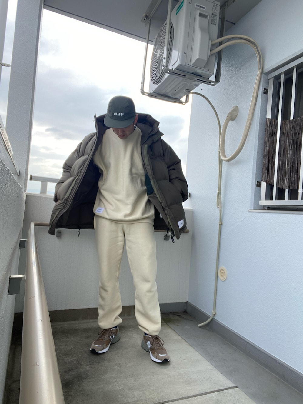 ベージュ系のスウェット、ホワイト系のスウェットパンツ、グリーン系のダウンジャケット/コートを着用したメンズの冬コーディネートの2枚目の写真