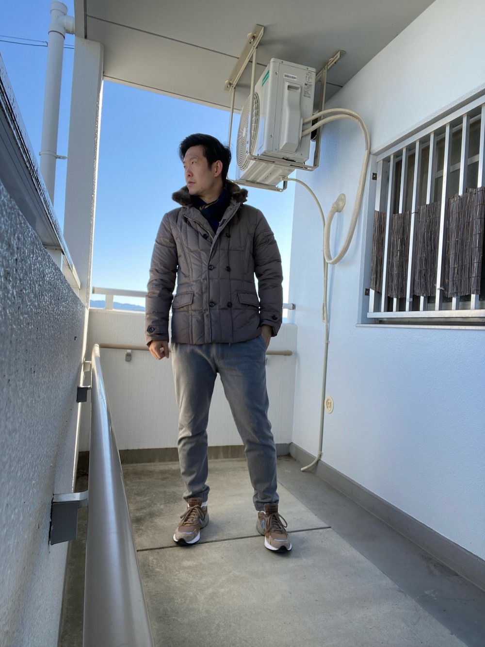 グレー系のスラックス、ベージュ系のダウンジャケット/コート、ベージュ系のスニーカーを着用したメンズの冬コーディネートの2枚目の写真