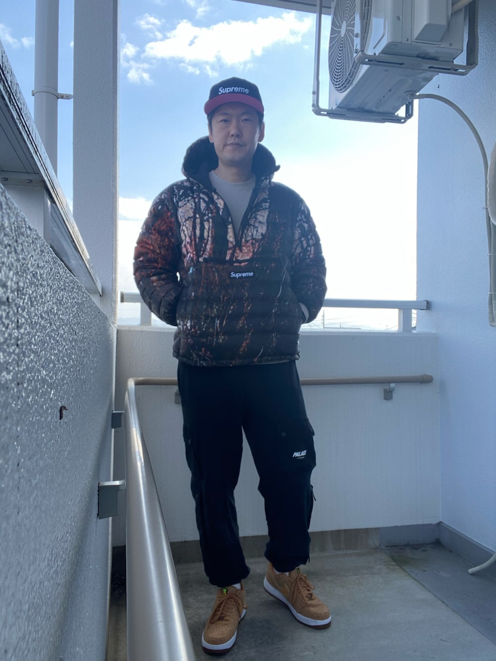 ブラック系のダウンジャケット/コート、グレー系のニット/セーター、ブラック系のスウェットパンツを着用したメンズの春コーディネートの2枚目の写真