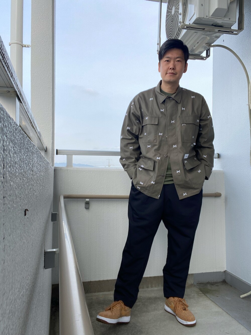 ブラック系のスラックス、ベージュ系のシャツ/ブラウス、ブラウン系のスニーカーを着用したメンズの春コーディネートの2枚目の写真