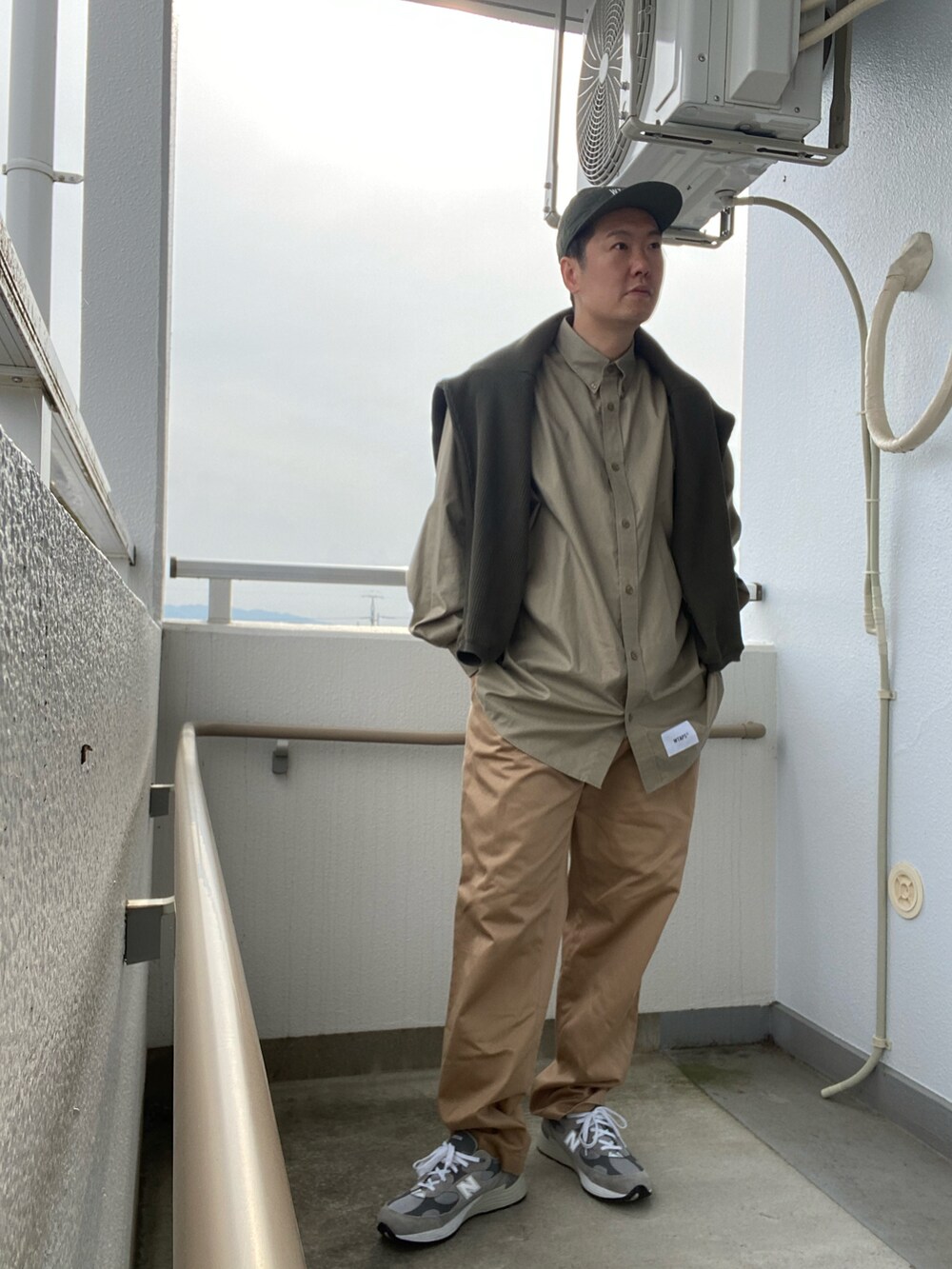 ベージュ系のシャツ/ブラウス、ベージュ系のチノパンツ、グレー系のスニーカーを着用したメンズの春コーディネートの2枚目の写真