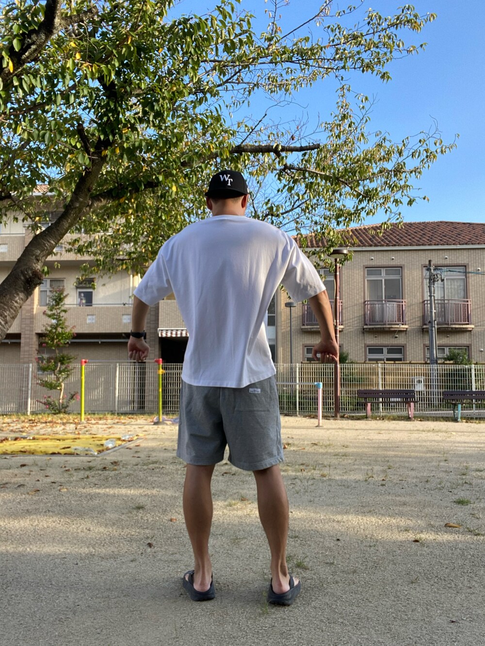 ホワイト系のTシャツ/カットソー、グレー系のその他パンツ、ブラック系のサンダルを着用したメンズの秋コーディネートの2枚目の写真