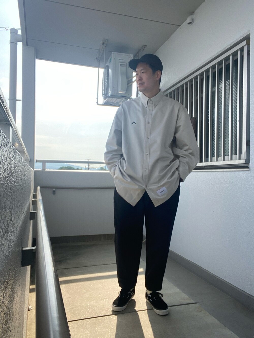 ブラック系のスラックス、グレー系のシャツ/ブラウス、ブラック系のスニーカーを着用したメンズの春コーディネートの2枚目の写真