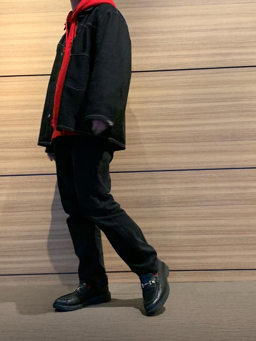 レッド系のパーカー、ブラック系のデニムジャケット、ブラック系のデニムパンツを着用したメンズの冬コーディネートの3枚目の写真