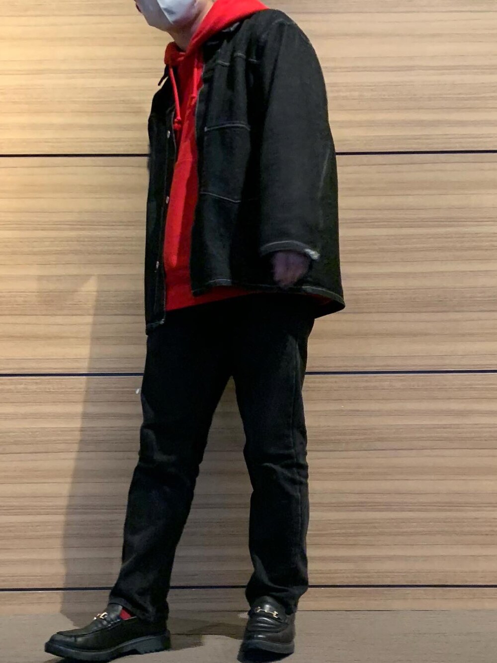 レッド系のパーカー、ブラック系のデニムジャケット、ブラック系のデニムパンツを着用したメンズの冬コーディネートの2枚目の写真