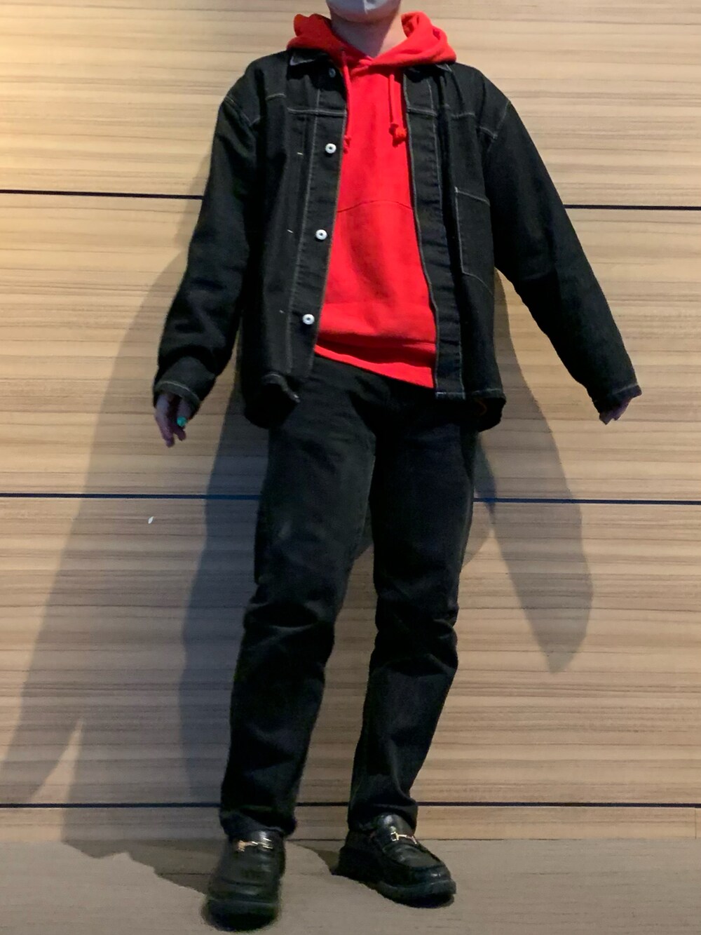 レッド系のパーカー、ブラック系のデニムジャケット、ブラック系のデニムパンツを着用したメンズの冬コーディネートの4枚目の写真