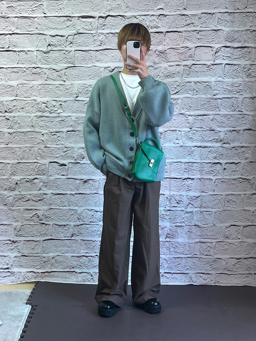 ブラウン系のスラックス、ブラック系のショルダーバッグ、ブラック系のドレスシューズを着用したメンズの冬コーディネートの2枚目の写真