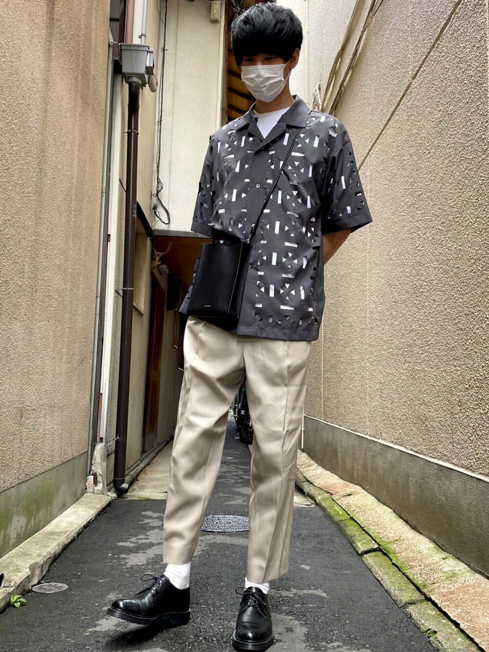 ベージュ系のスラックス、ブラック系のドレスシューズ、ブラック系のショルダーバッグを着用したメンズの夏コーディネートの3枚目の写真