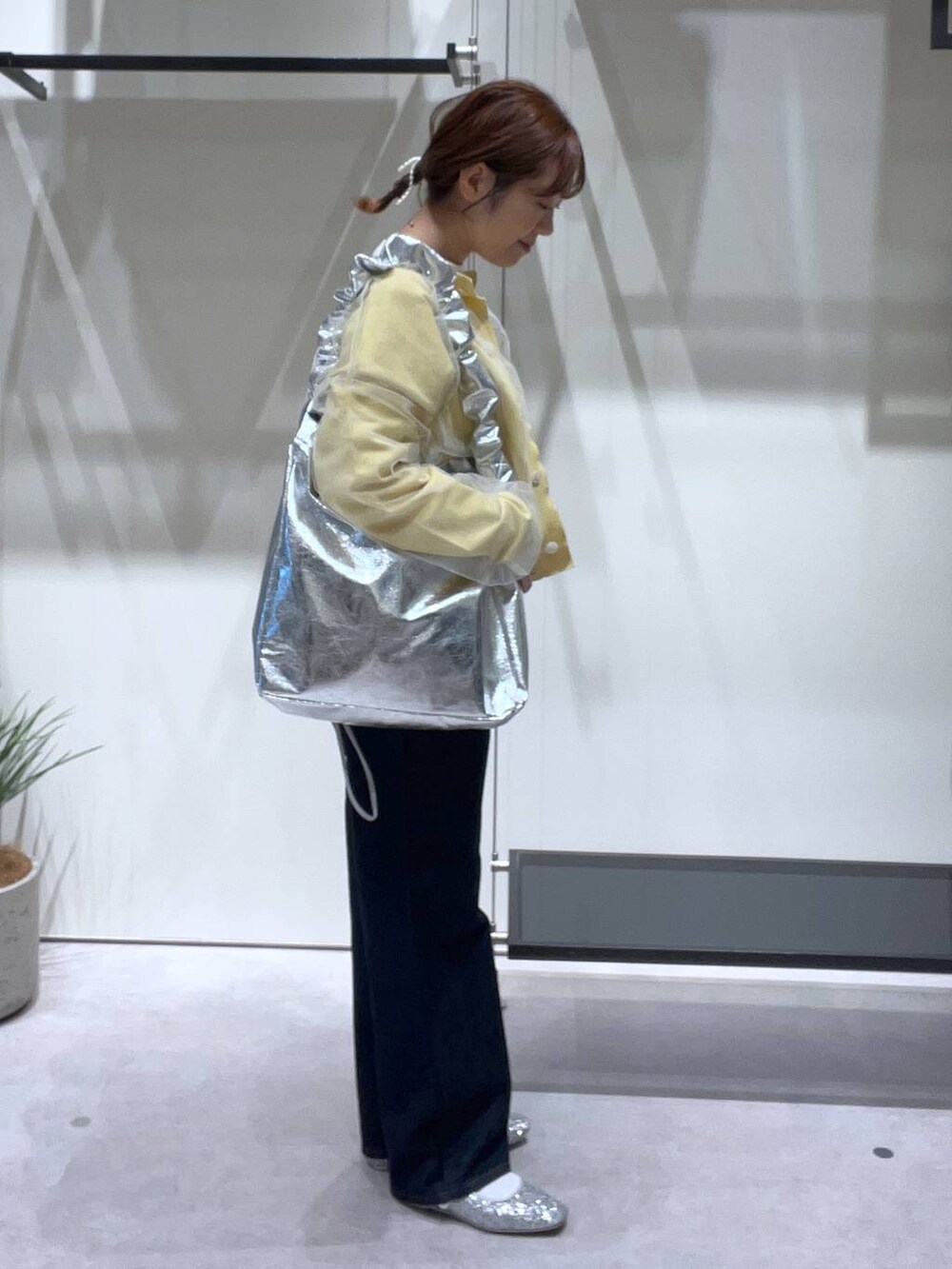 グレー系のトートバッグ、シルバー系のパンプス、ブルー系のデニムパンツを着用したレディースの春コーディネートの2枚目の写真