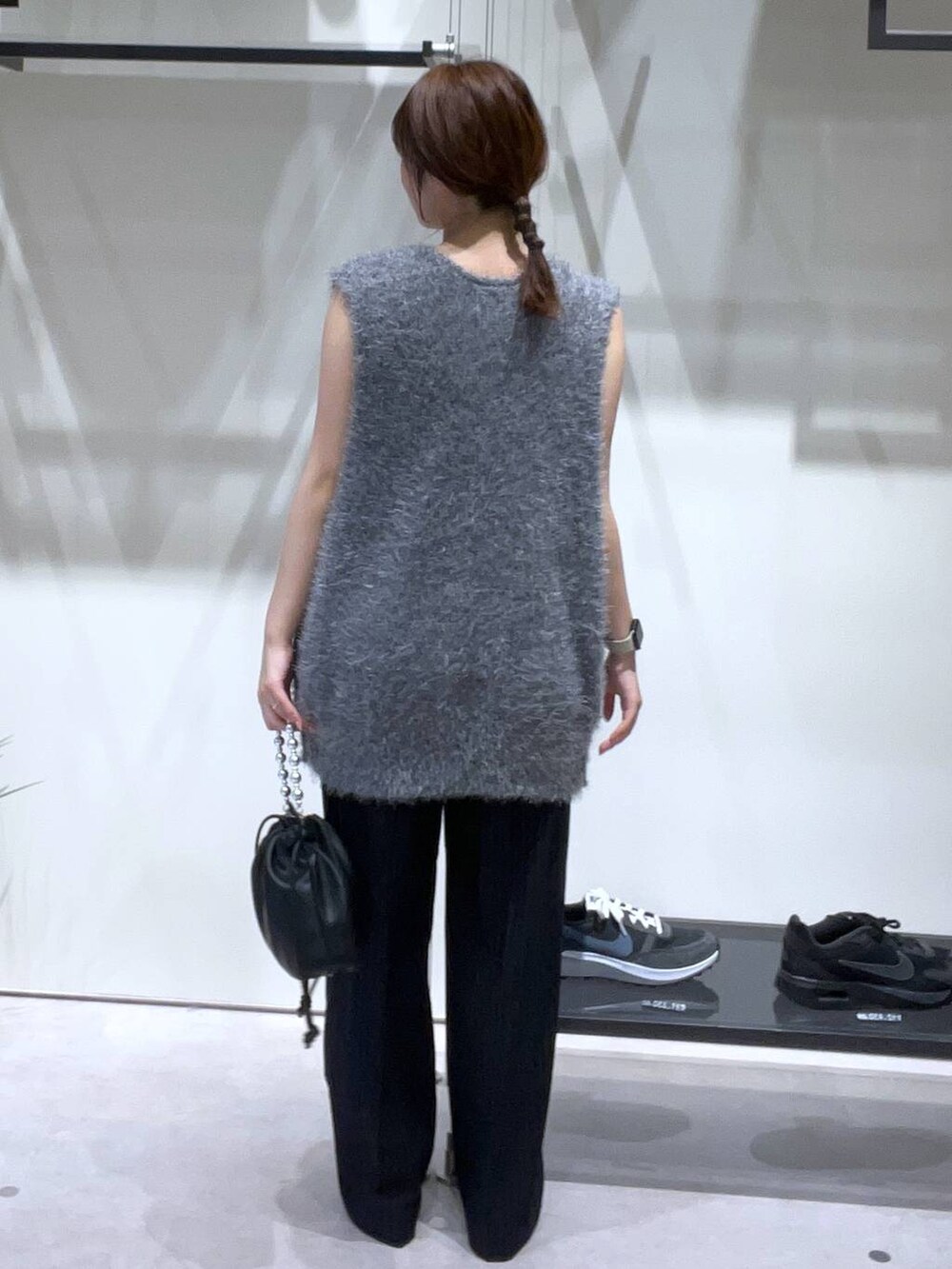 ブラック系のスラックス、ブラック系のパンプス、ブラック系のショルダーバッグを着用したレディースの夏コーディネートの3枚目の写真