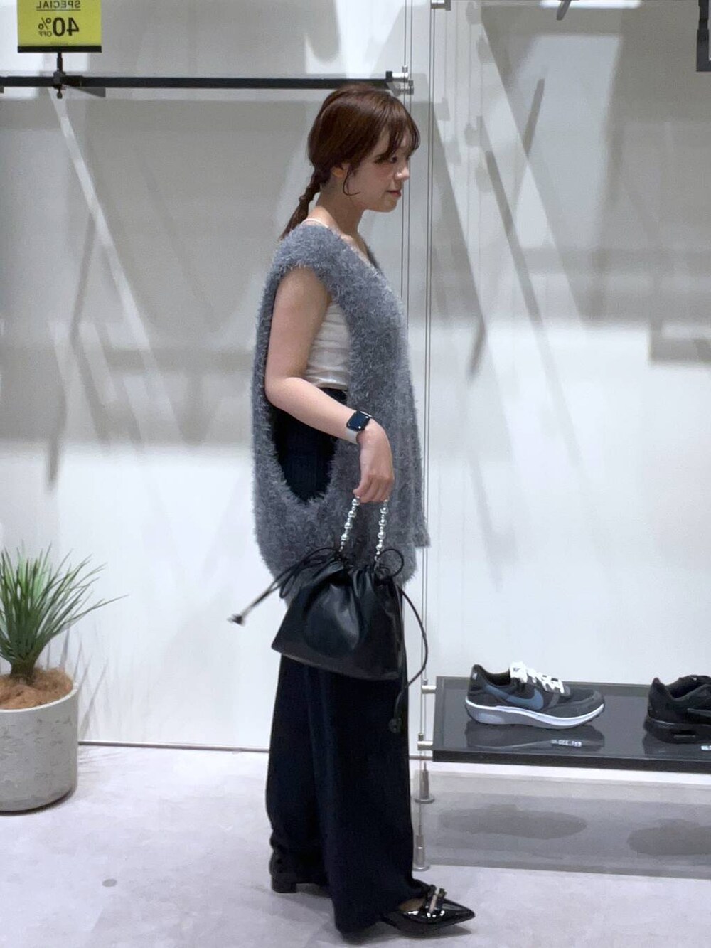 ブラック系のスラックス、ブラック系のパンプス、ブラック系のショルダーバッグを着用したレディースの夏コーディネートの2枚目の写真