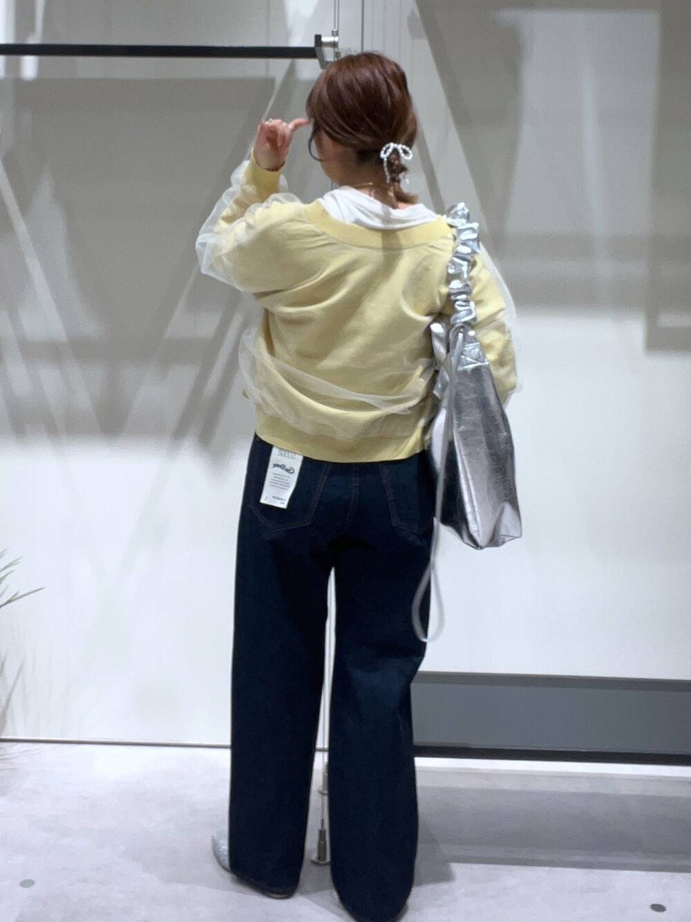 グレー系のトートバッグ、シルバー系のパンプス、ブルー系のデニムパンツを着用したレディースの春コーディネートの3枚目の写真