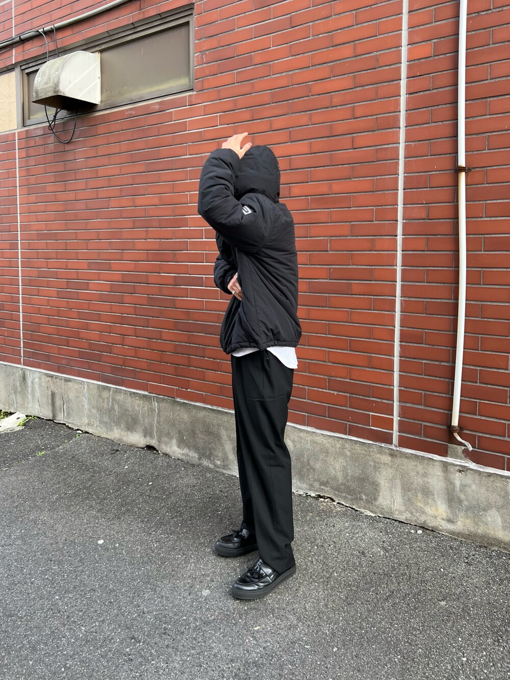 ブラック系のダウンジャケット/コート、ブラック系のその他パンツ、ブラウン系のサングラスを着用したメンズの秋コーディネートの3枚目の写真