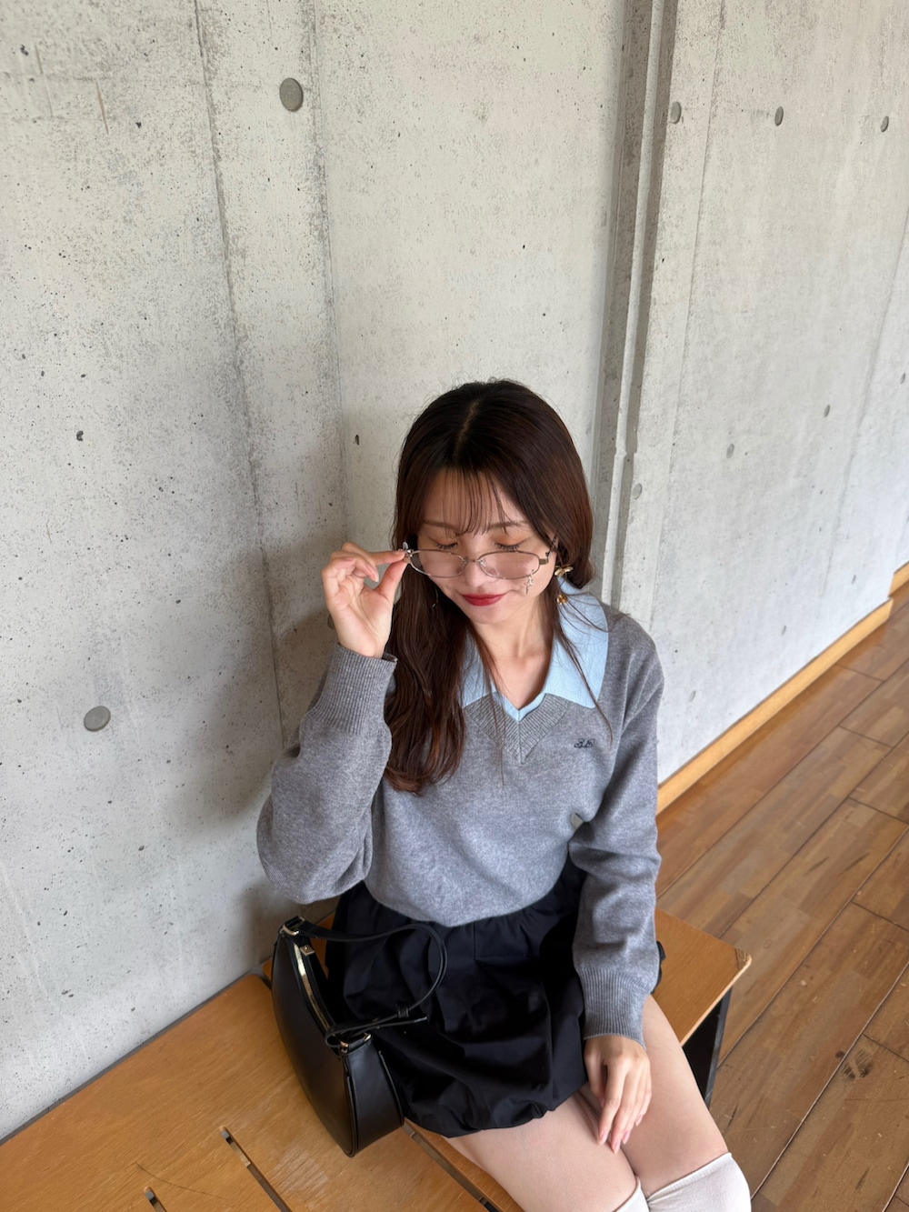 グレー系のニット/セーター、ブラック系のスカート、ブラック系のスニーカーを着用したレディースの秋コーディネートの2枚目の写真