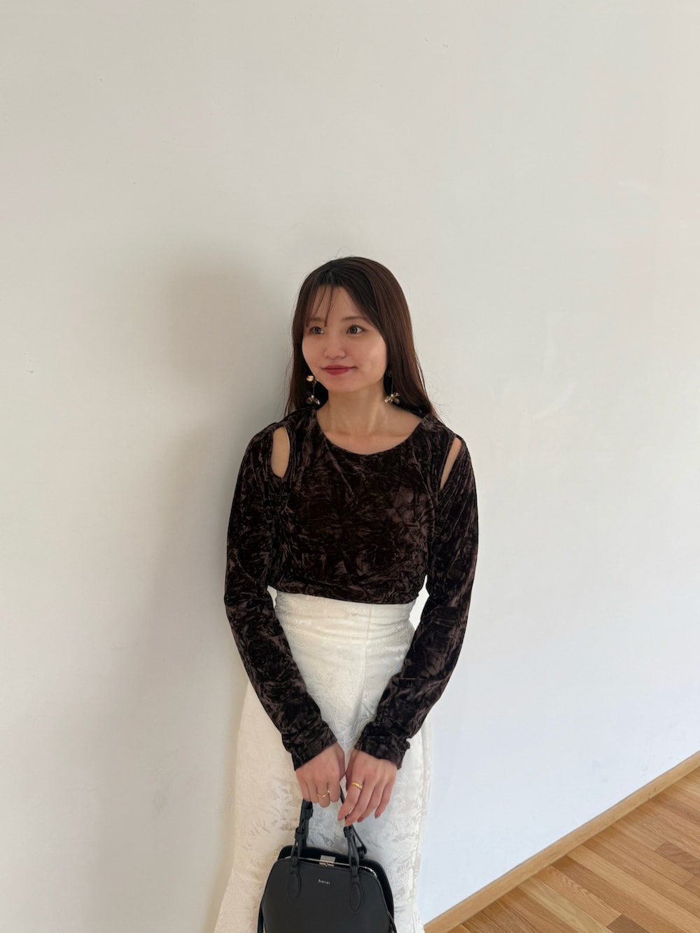 ブラウン系のTシャツ/カットソー、ホワイト系のスカート、ブラック系のハンドバッグを着用したレディースの秋コーディネートの2枚目の写真