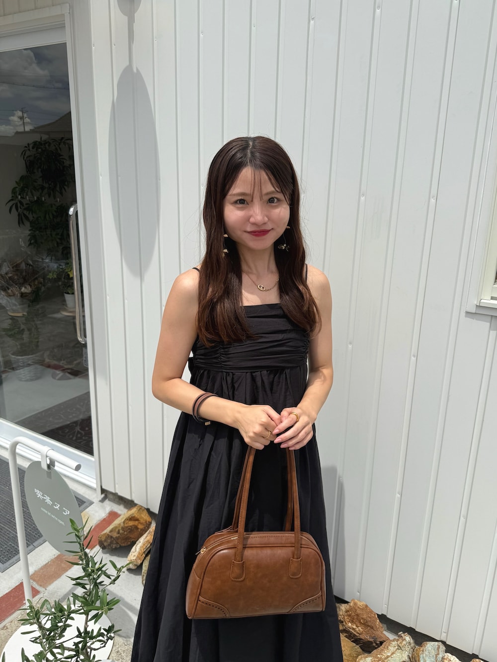 イエロー系のボストンバッグ、ホワイト系のパンプス、ブラック系のワンピース/ドレスを着用したレディースの夏コーディネートの2枚目の写真