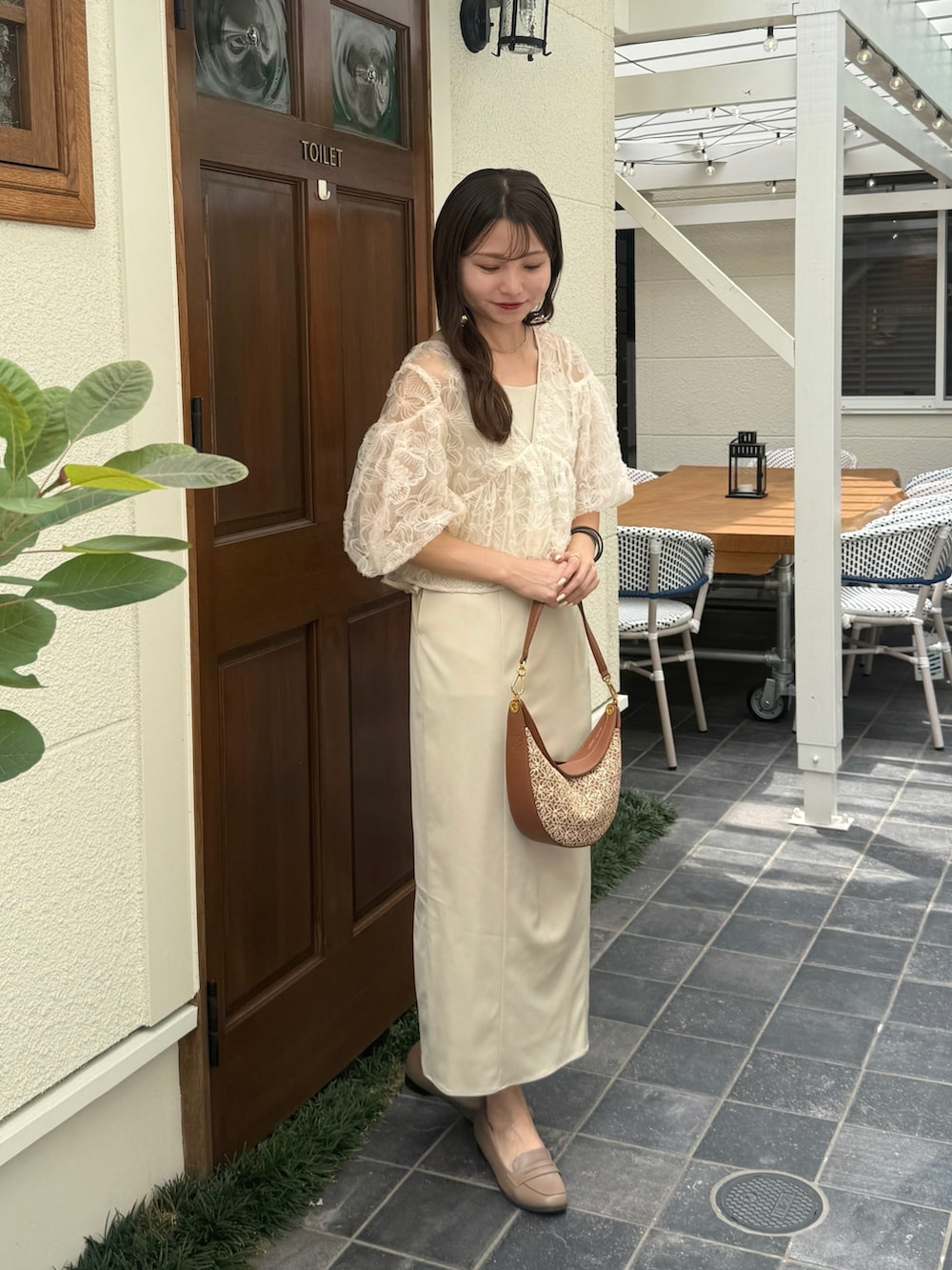 ベージュ系のドレス、ブラウン系のハンドバッグ、ブラウン系のパンプスを着用したレディースの夏コーディネートの2枚目の写真