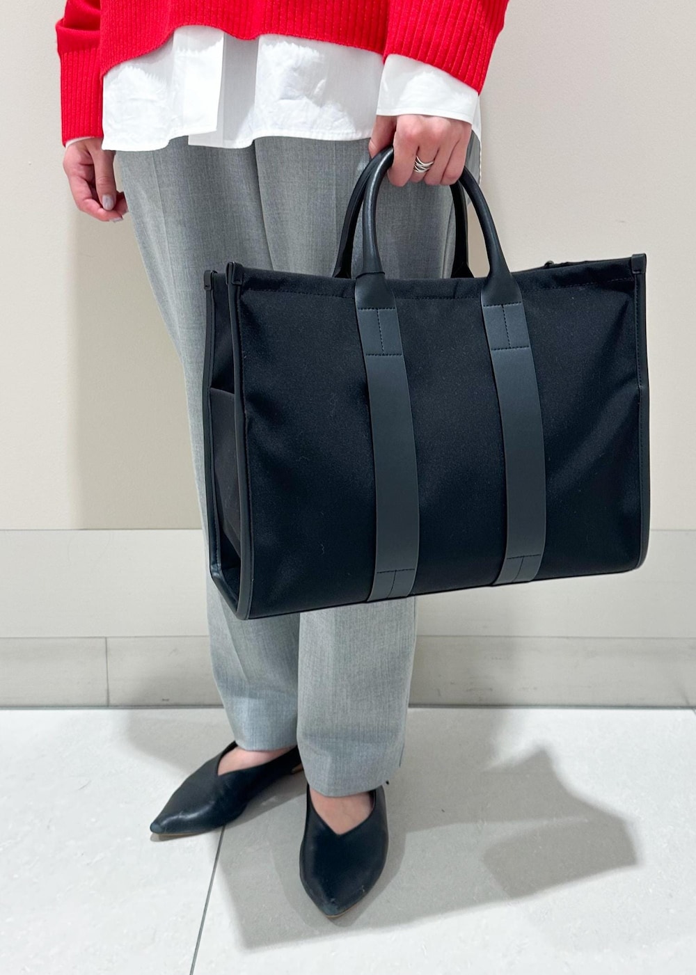 ブラック系のトートバッグ、ホワイト系のシャツ/ブラウス、レッド系のニット/セーターを着用したレディースの冬コーディネートの7枚目の写真