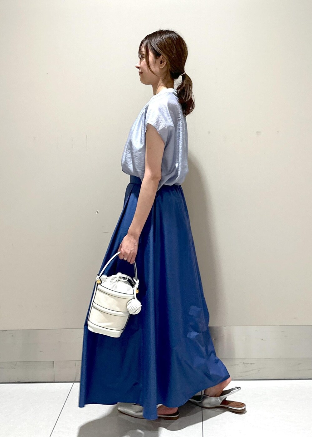 ホワイト系のハンドバッグ、シルバー系のパンプス、ブルー系のシャツ/ブラウスを着用したレディースの夏コーディネートの2枚目の写真