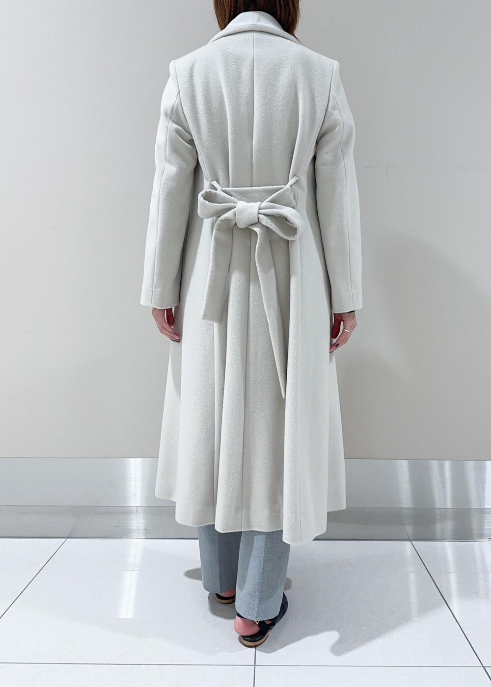 オレンジ系のハンドバッグ、ホワイト系のチェスターコート、グレー系のその他パンツを着用したレディースの秋コーディネートの6枚目の写真