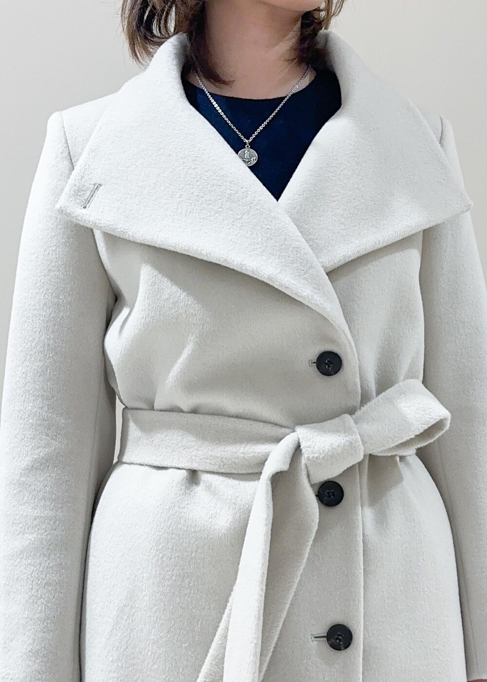 オレンジ系のハンドバッグ、ホワイト系のチェスターコート、グレー系のその他パンツを着用したレディースの秋コーディネートの7枚目の写真