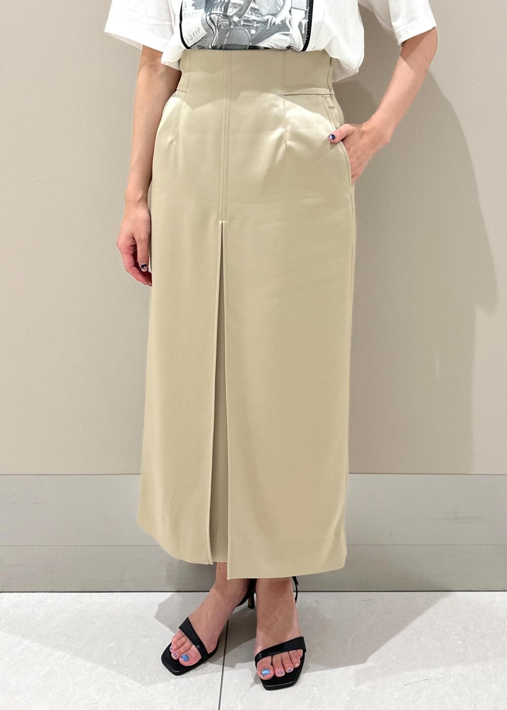 ブラック系のハンドバッグ、ブラック系のサンダル、ベージュ系のスカートを着用したレディースの夏コーディネートの7枚目の写真