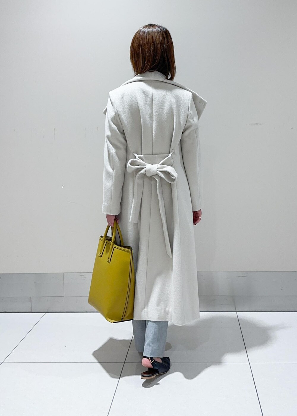 オレンジ系のハンドバッグ、ホワイト系のチェスターコート、グレー系のその他パンツを着用したレディースの秋コーディネートの3枚目の写真