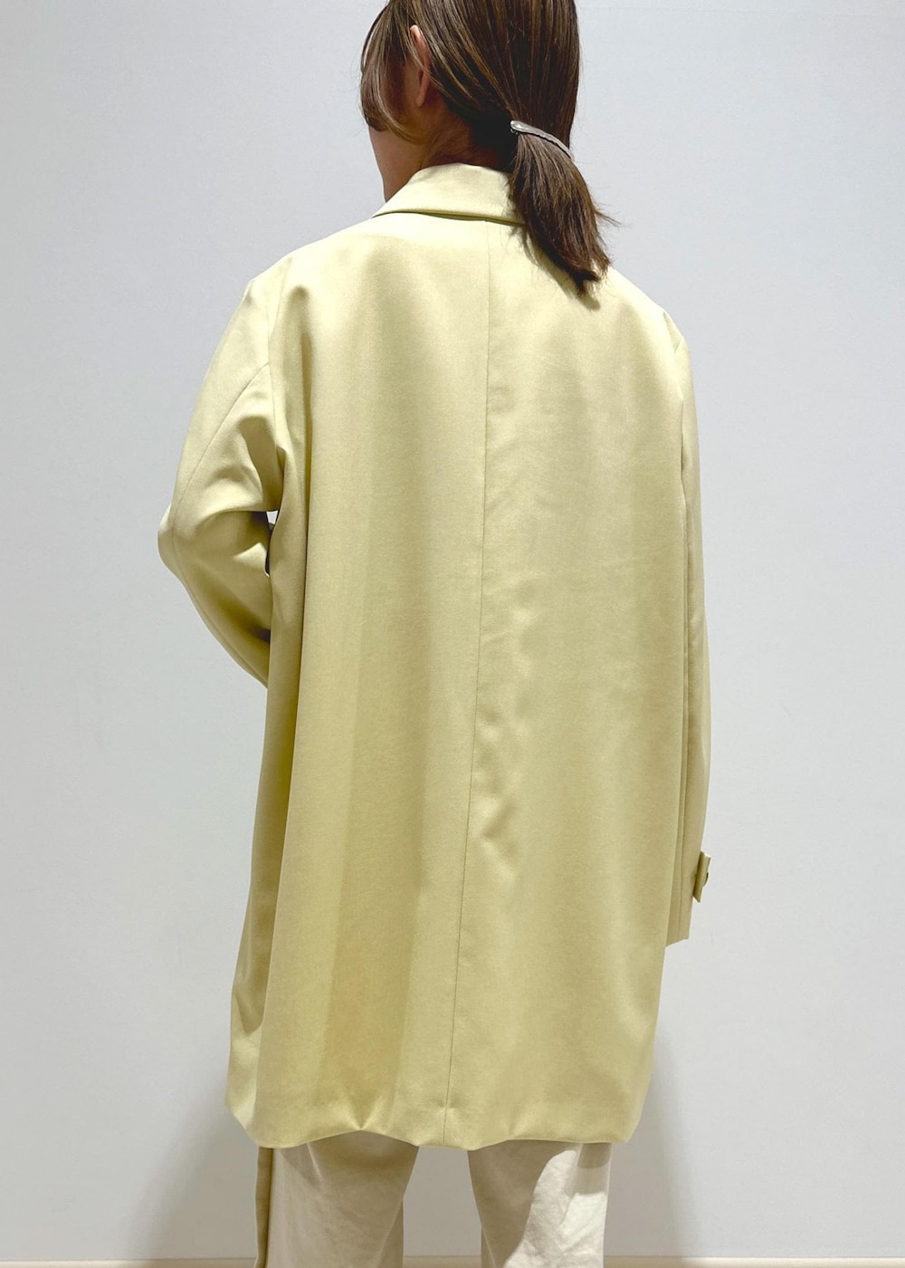 ホワイト系のハンドバッグ、ベージュ系のステンカラーコート、ホワイト系のその他パンツを着用したレディースの春コーディネートの6枚目の写真