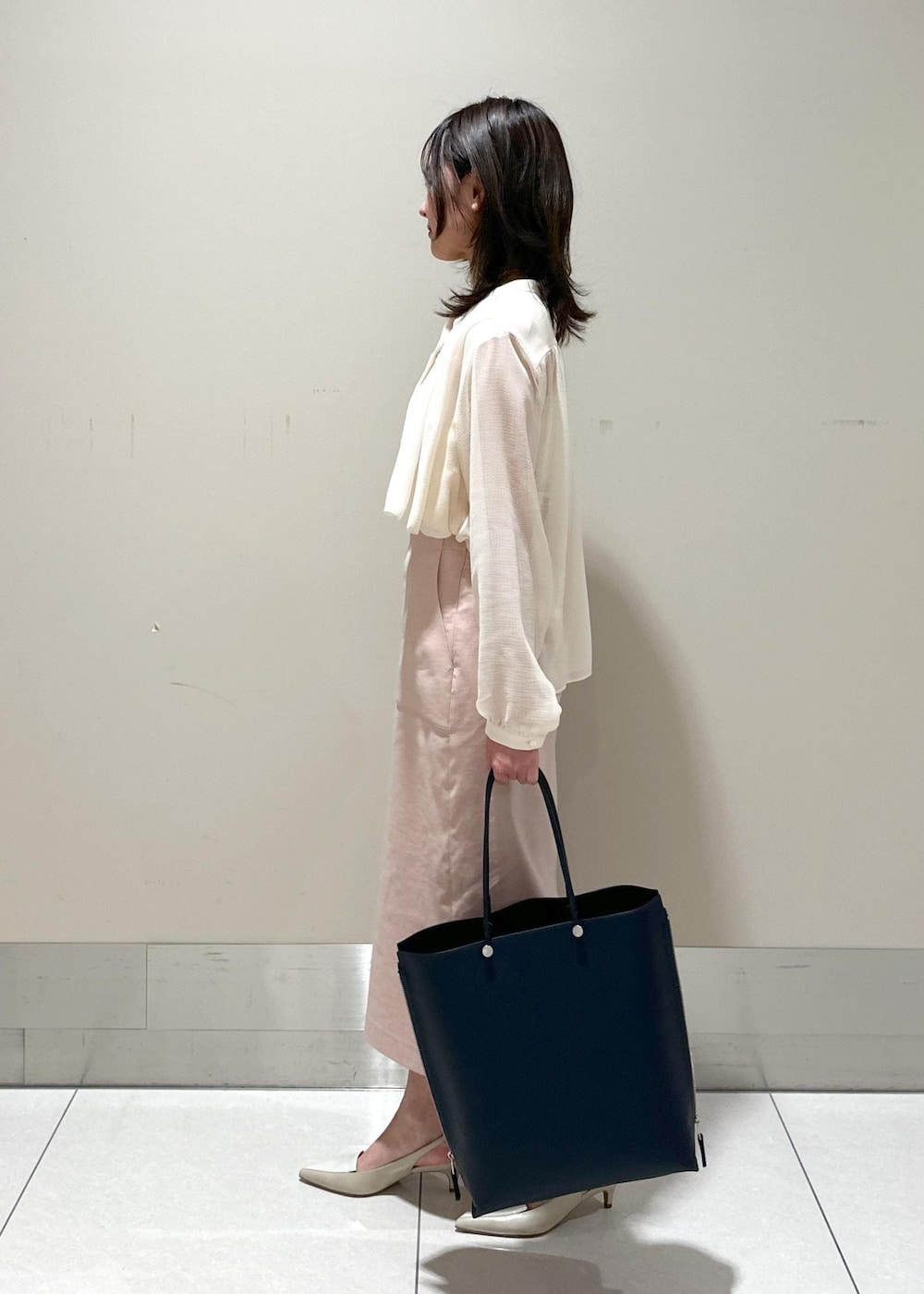 ブルー系のトートバッグ、ベージュ系のパンプス、ホワイト系のシャツ/ブラウスを着用したレディースの春コーディネートの2枚目の写真