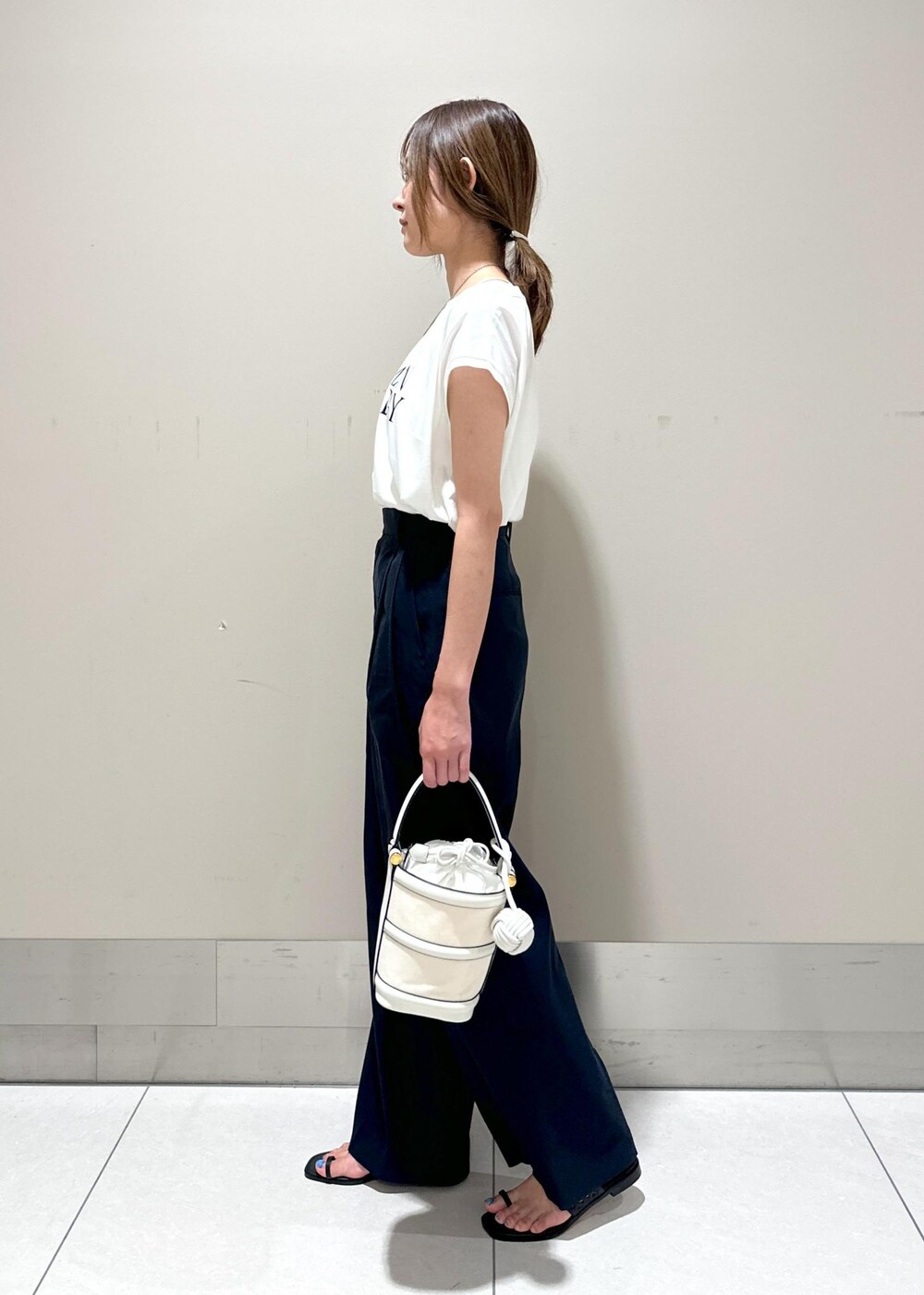 ホワイト系のハンドバッグ、ブラック系のサンダル、ブルー系のその他パンツを着用したレディースの夏コーディネートの2枚目の写真