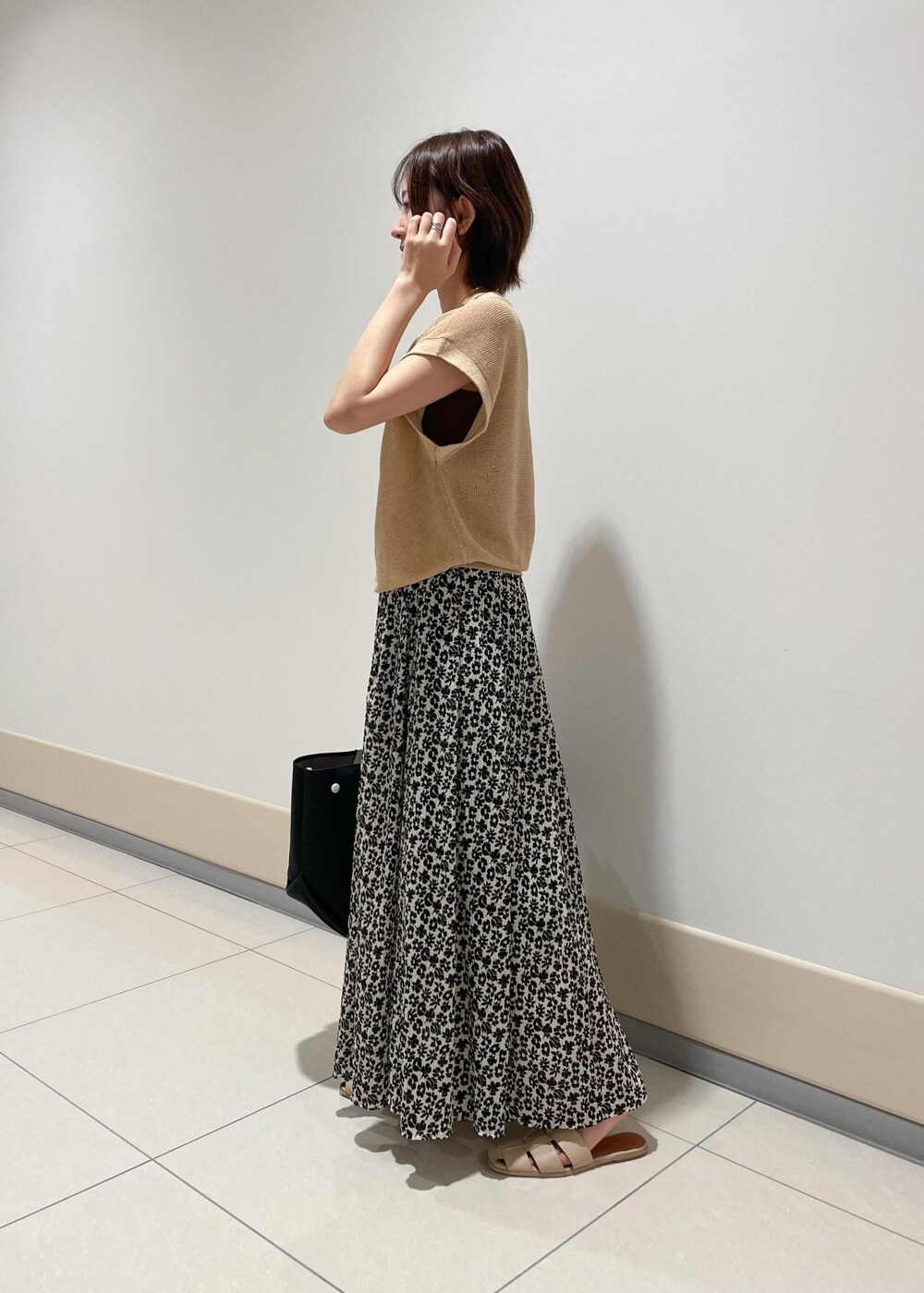 ブラック系のハンドバッグ、ベージュ系のTシャツ/カットソー、ブラック系のスカートを着用したレディースの夏コーディネートの2枚目の写真