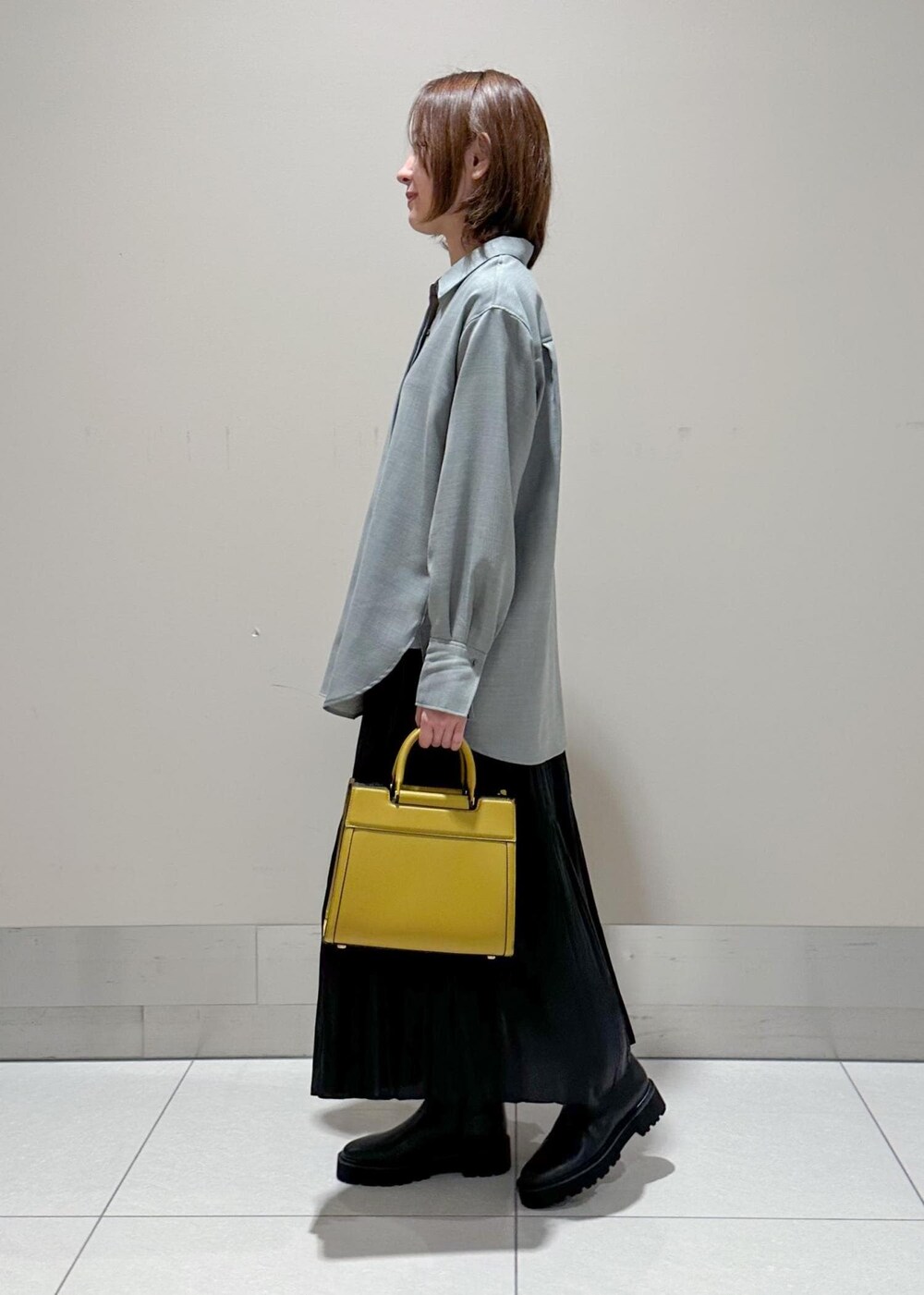 イエロー系のハンドバッグ、グレー系のシャツ/ブラウス、ブラック系のスカートを着用したレディースの秋コーディネートの2枚目の写真