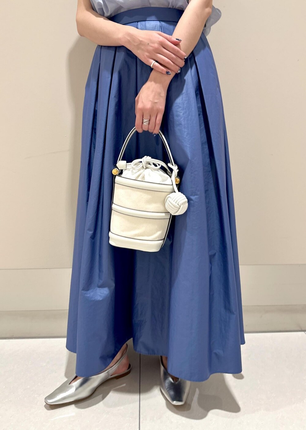 ホワイト系のハンドバッグ、シルバー系のパンプス、ブルー系のシャツ/ブラウスを着用したレディースの夏コーディネートの7枚目の写真