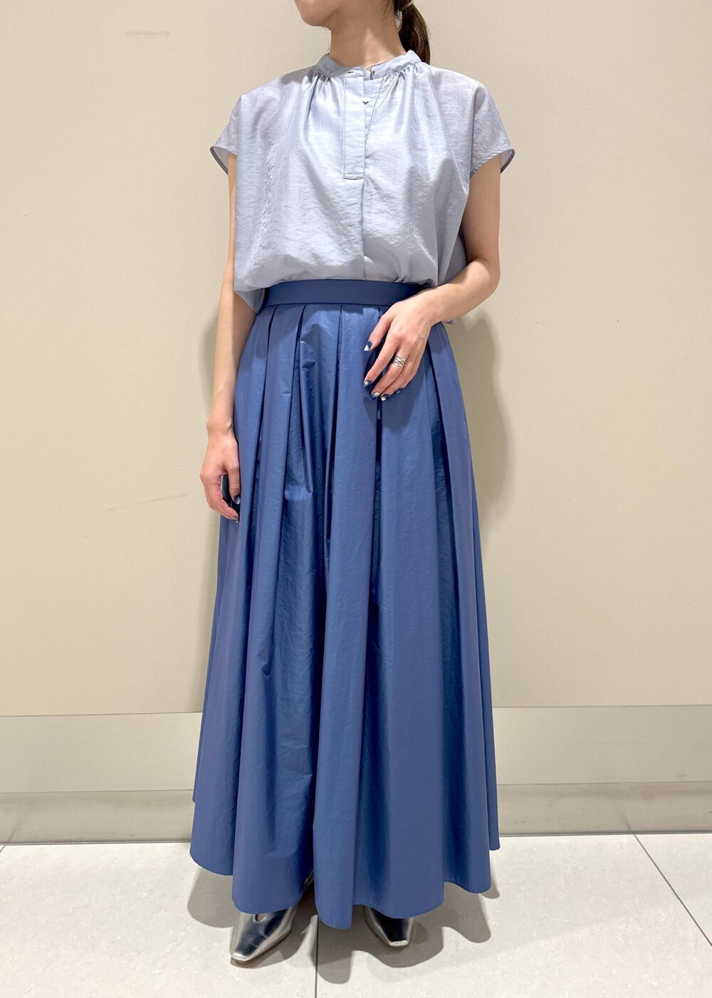 ホワイト系のハンドバッグ、シルバー系のパンプス、ブルー系のシャツ/ブラウスを着用したレディースの夏コーディネートの4枚目の写真