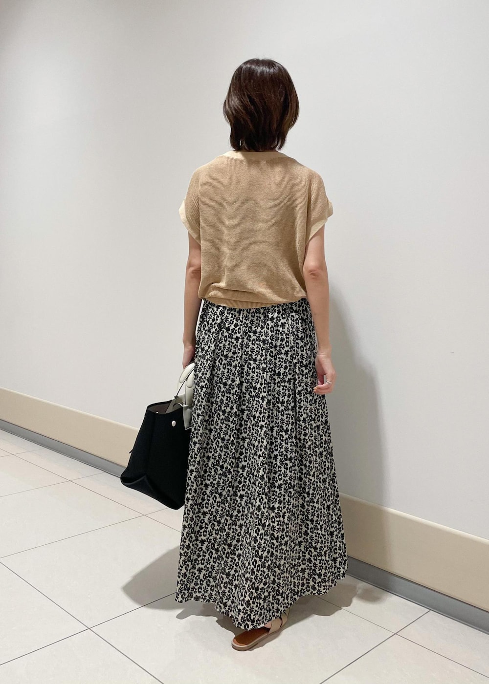 ブラック系のハンドバッグ、ベージュ系のTシャツ/カットソー、ブラック系のスカートを着用したレディースの夏コーディネートの3枚目の写真