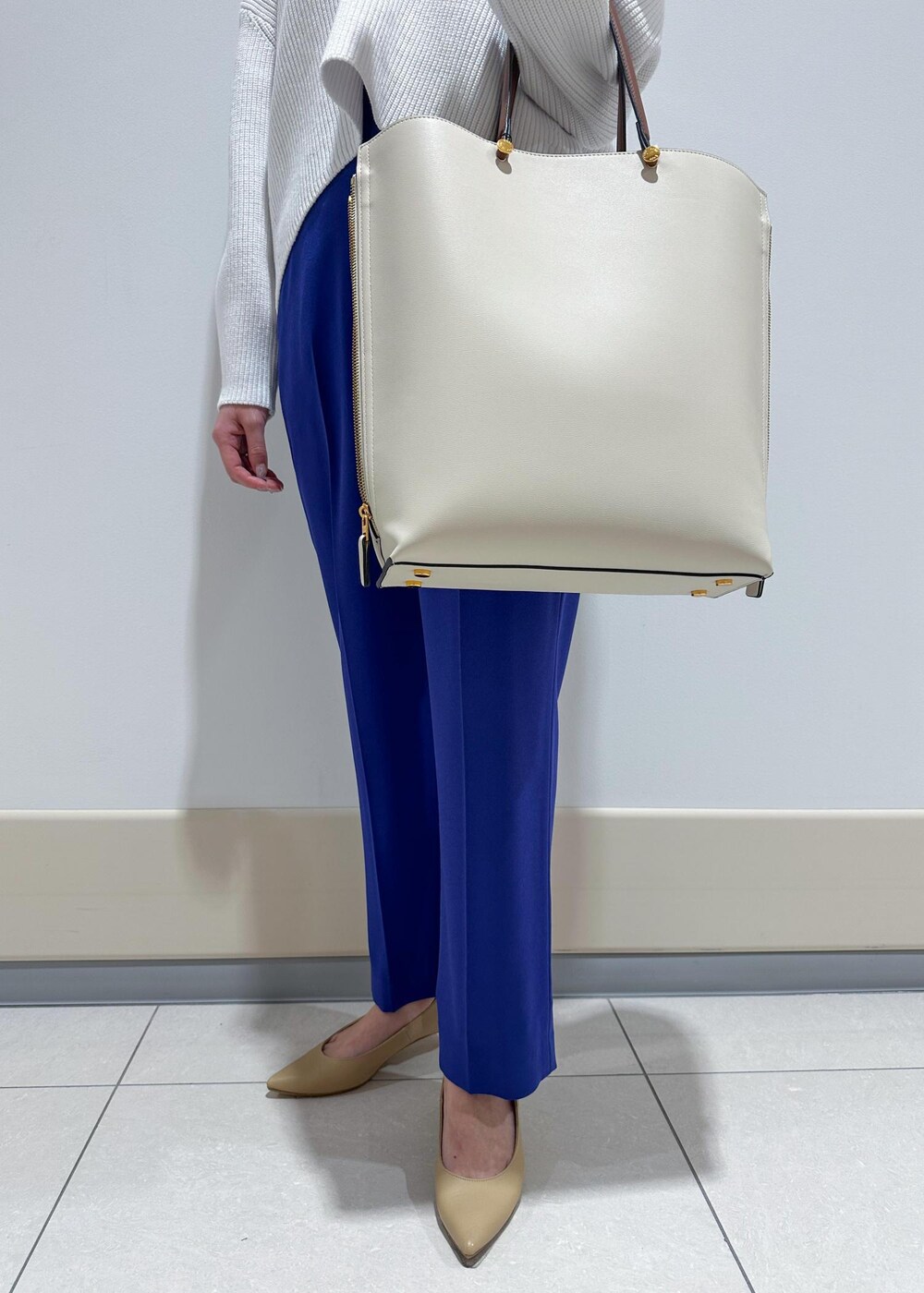 ベージュ系のパンプス、ホワイト系のトートバッグ、ブルー系のその他パンツを着用したレディースの冬コーディネートの7枚目の写真