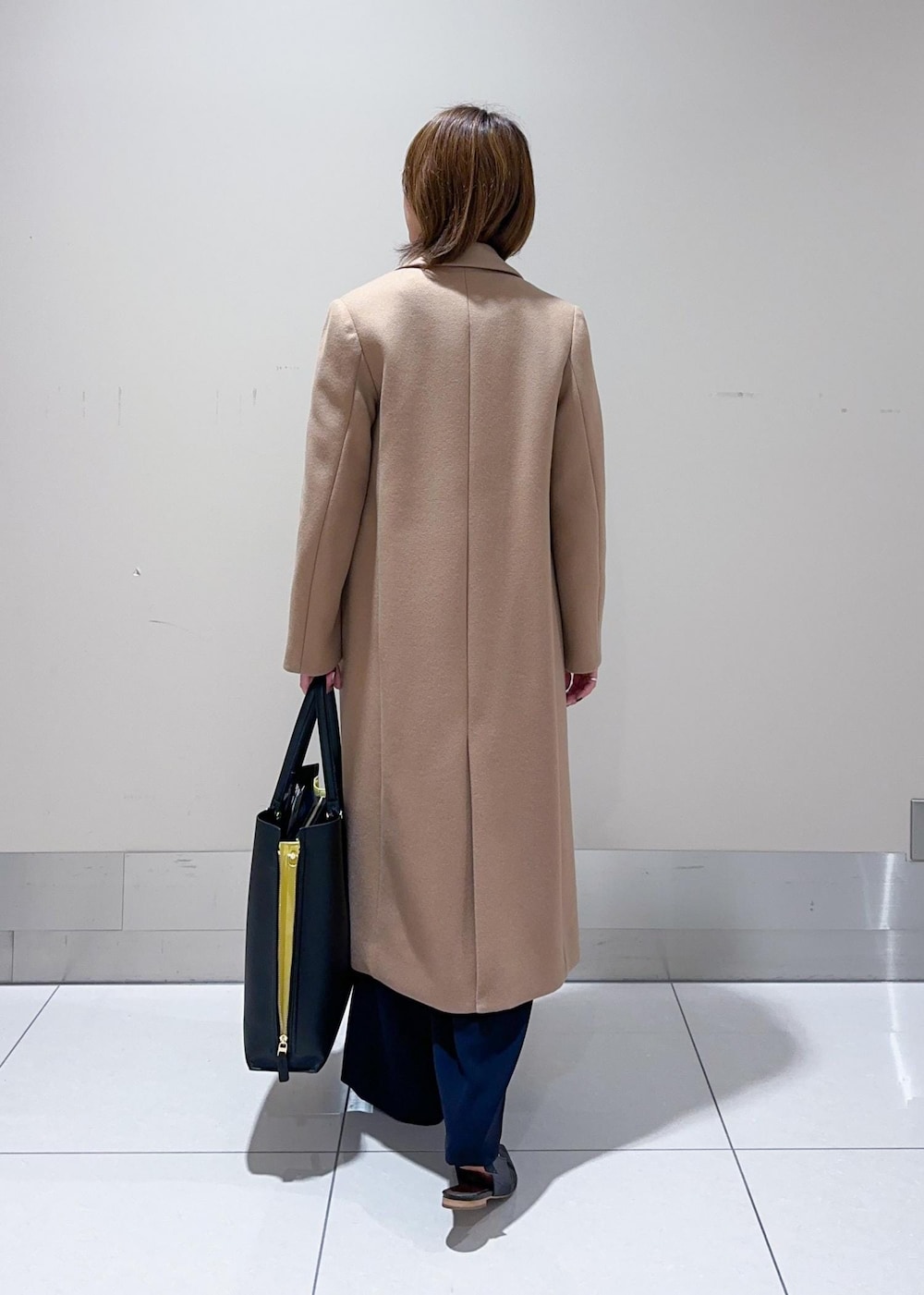 ブラック系のトートバッグ、イエロー系のチェスターコート、ブラウン系のニット/セーターを着用したレディースの秋コーディネートの3枚目の写真