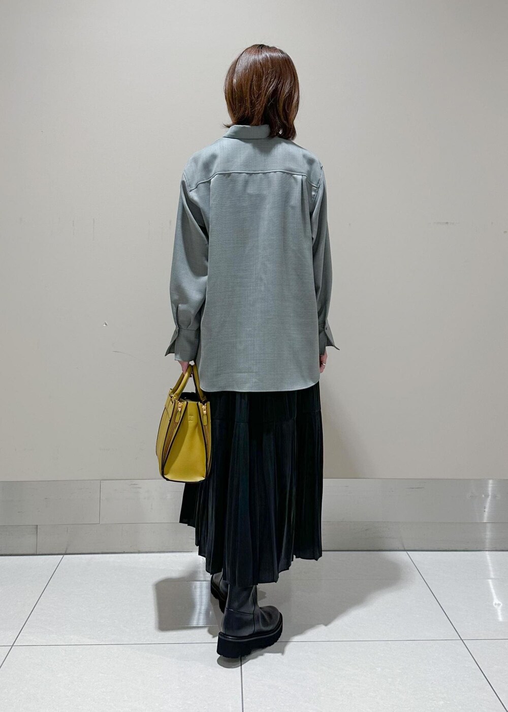 イエロー系のハンドバッグ、グレー系のシャツ/ブラウス、ブラック系のスカートを着用したレディースの秋コーディネートの3枚目の写真