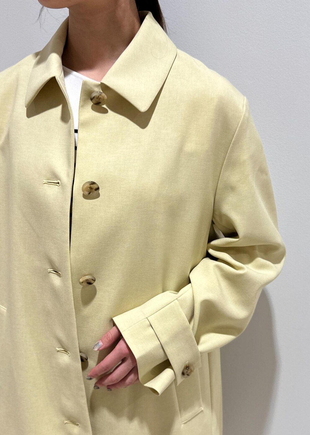 ホワイト系のハンドバッグ、ベージュ系のステンカラーコート、ホワイト系のその他パンツを着用したレディースの春コーディネートの5枚目の写真