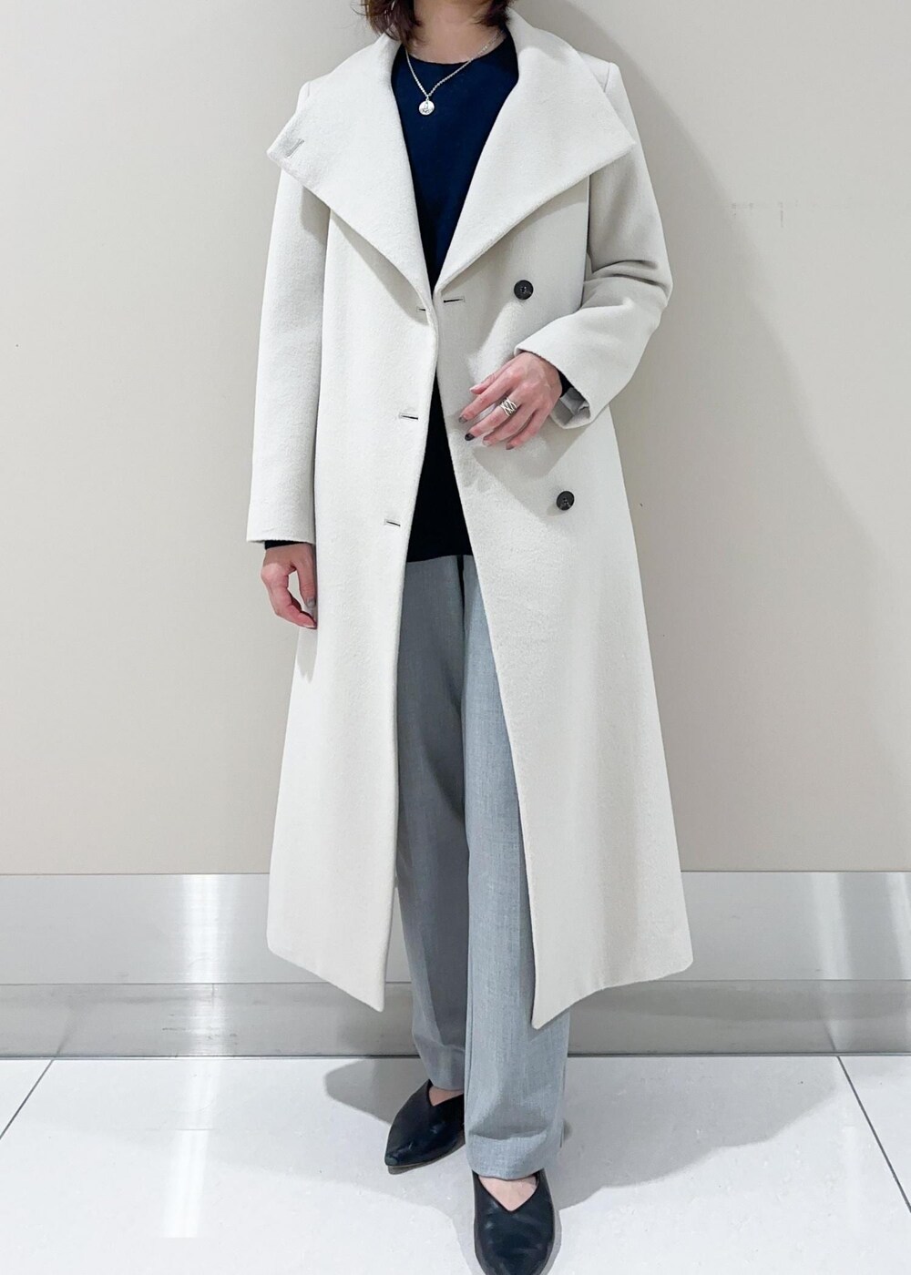 オレンジ系のハンドバッグ、ホワイト系のチェスターコート、グレー系のその他パンツを着用したレディースの秋コーディネートの4枚目の写真