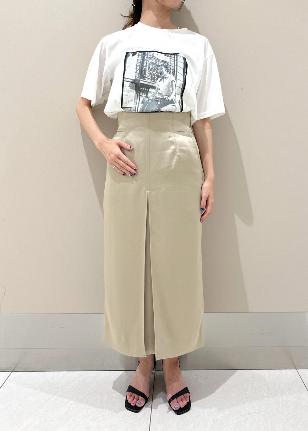 ブラック系のハンドバッグ、ブラック系のサンダル、ベージュ系のスカートを着用したレディースの夏コーディネートの4枚目の写真