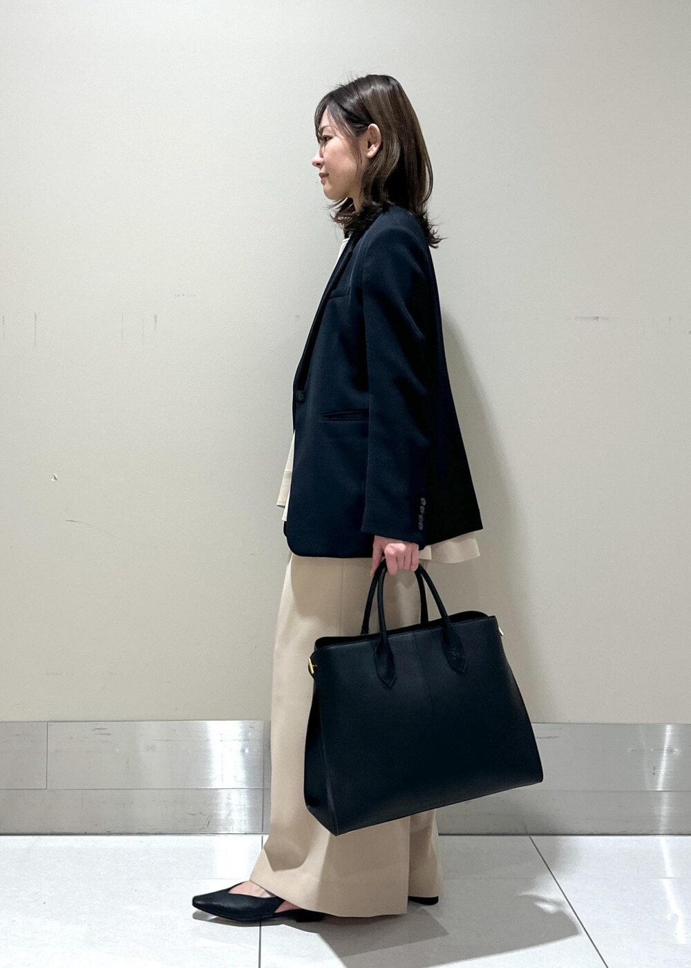 ブルー系のテーラードジャケット、ブラック系のパンプス、ブラック系のトートバッグを着用したレディースの春コーディネートの2枚目の写真