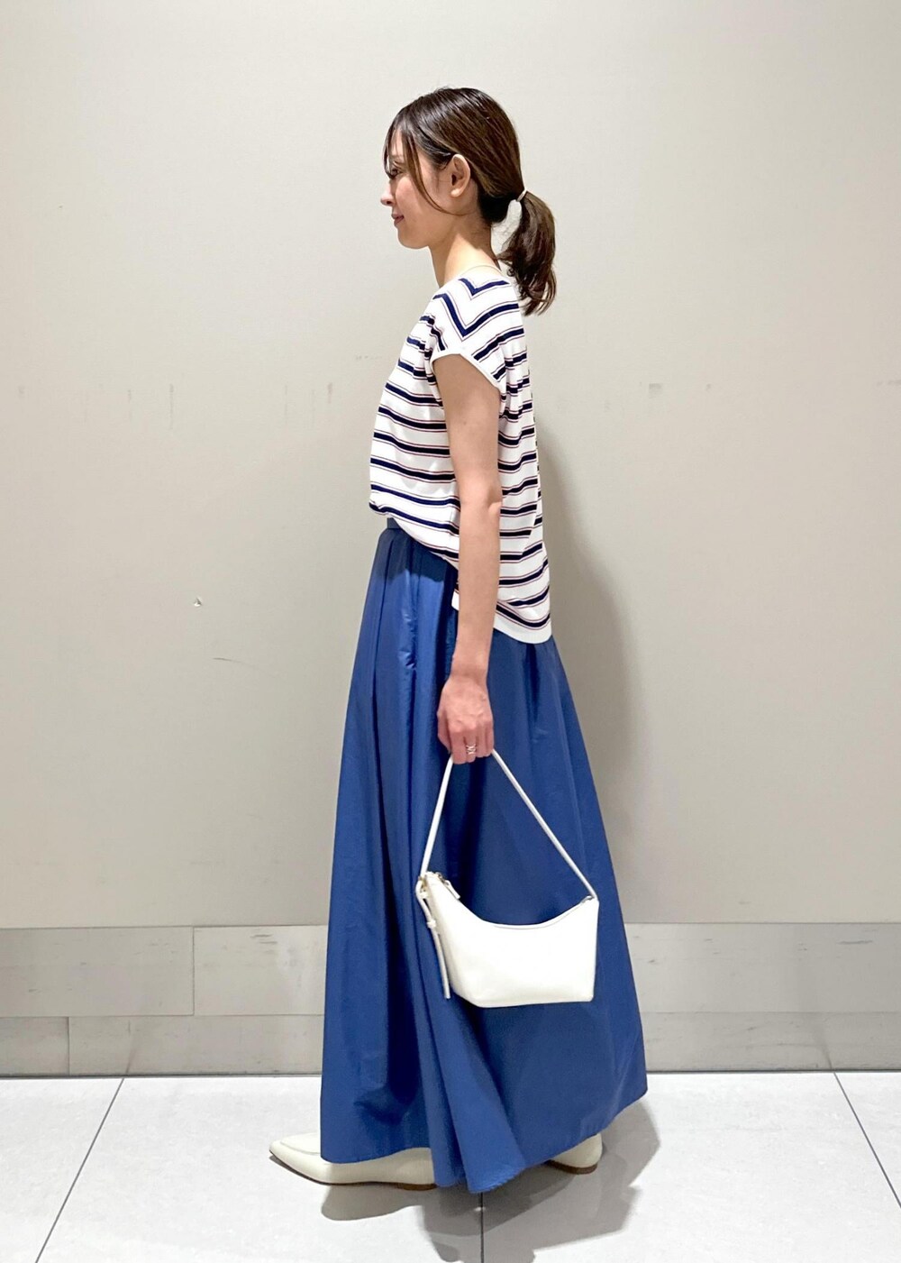 ホワイト系のハンドバッグ、ホワイト系のパンプス、ホワイト系のニット/セーターを着用したレディースの夏コーディネートの2枚目の写真